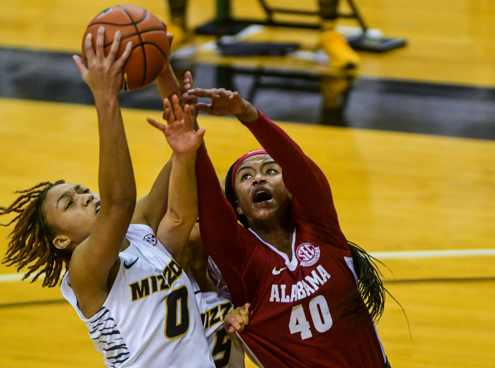 Alabama forward Jasmine Walker, right, reaches for the ball as University of Missouri forward LaDazhia Williams grabs onto it